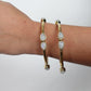 Teardrop Moonstone Brass Cuff - Sleek gold-tone brass cuff with teardrop moonstones in minimalist design.