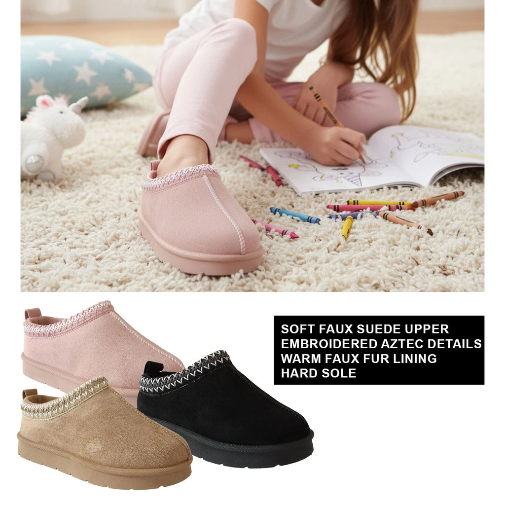 Children's pink slippers with embroidered aztec details, worn by a child sitting on the floor with coloring books and crayons.